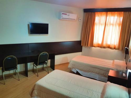 a hotel room with two beds and a desk at Dom Pedro I Palace Hotel in Foz do Iguaçu