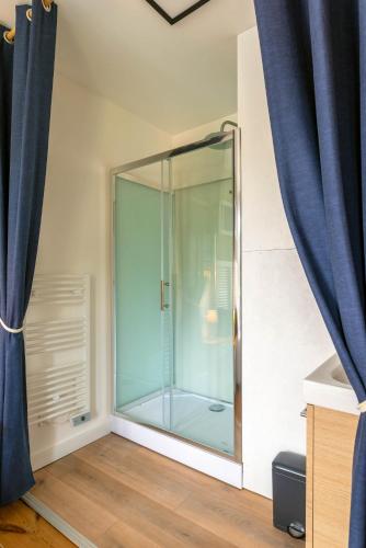 - une douche en verre dans une chambre dotée de rideaux bleus dans l'établissement La lisette, à Étretat