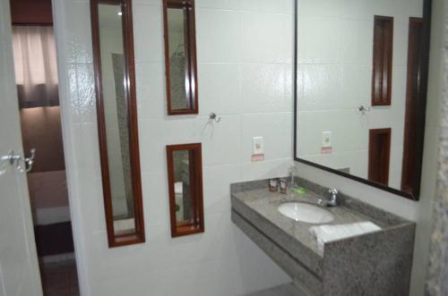 a bathroom with a sink and mirrors on the wall at Motel & Hotel Free Love JF in Juiz de Fora