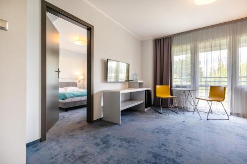 a bedroom with a desk and a bed and a mirror at Hotel Perłowy in Okuninka