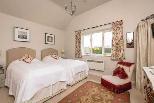1 dormitorio con 2 camas, ventana y silla en Wayside House B&B, en Whichford