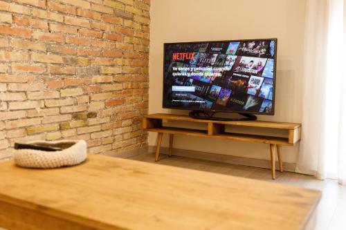 a living room with a tv and a brick wall at Lo passeig in Tremp