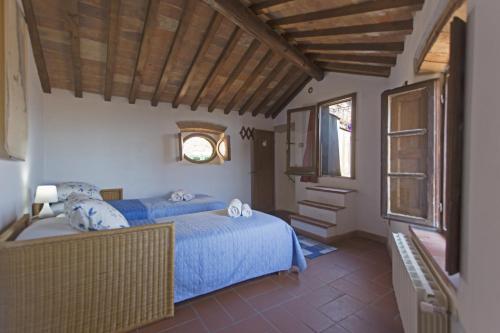 1 dormitorio con 2 camas azules y ventana en La Nave, en Casale Marittimo