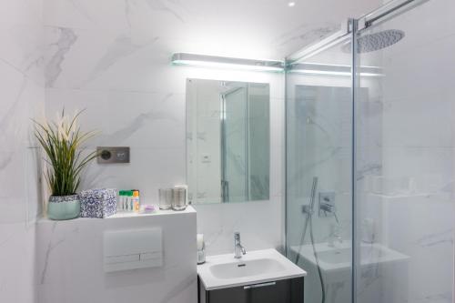 a white bathroom with a sink and a shower at Apartament Koszykowa Latwiec in Warsaw