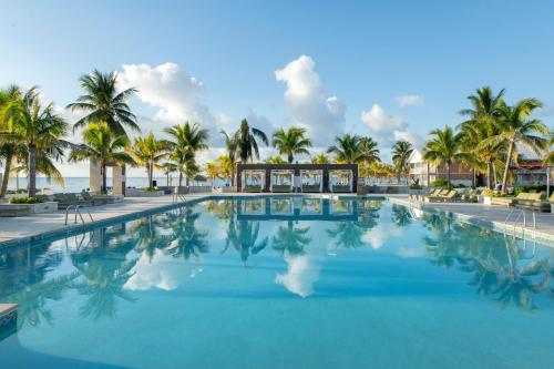 a swimming pool with palm trees and the ocean at Viva Fortuna Beach by Wyndham, A Trademark All Inclusive in Freeport