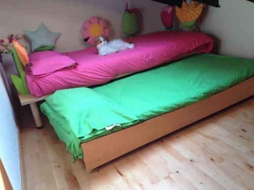 Una cama con sábanas rosas y verdes y un animal de peluche. en Can Taga Verd St Joan, en Sant Joan de les Abadesses