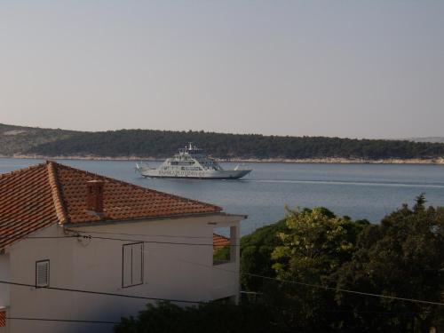 a boat in the water with a building and a house at Apartments Stengl in Rab