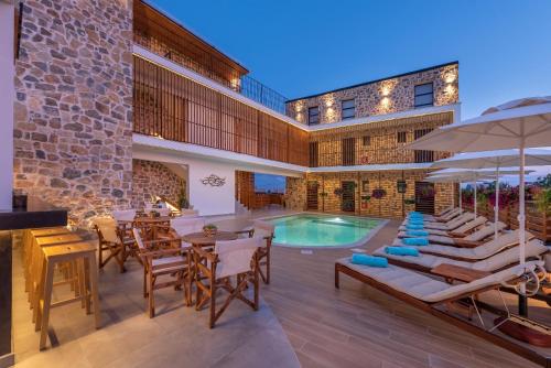 un patio al aire libre con piscina, mesas y sillas en Dandelion Suites en Nikiti