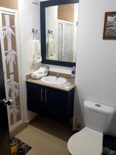 a bathroom with a sink and a toilet and a mirror at ARENA PLAZA DEPARTAMENTO PLAYA con vista al mar in Tonsupa