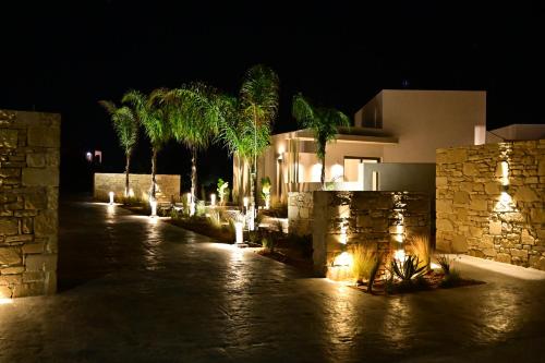 a house with palm trees and lights at night at Kavos Hotel & Suites in Stavros