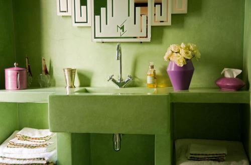 Un baño verde con un lavabo y un jarrón de flores. en Riad Le J, en Marrakech