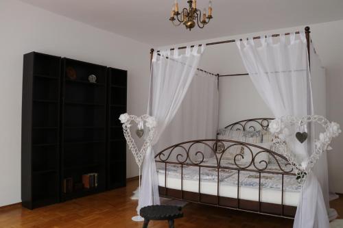 a bedroom with a bed with white curtains and a chandelier at The Lakehouse Villa Neusiedl am See Wienerstraße 8 in Neusiedl am See