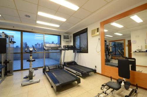 un gimnasio con equipo cardiovascular y una gran ventana en Union Residence HEER, en Novo Hamburgo