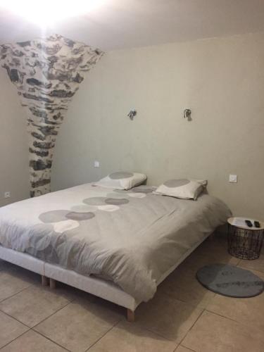 a large bed in a room with a stone wall at Chambres d'Hôtes du Villaret in Saint-Vincent-les-Forts