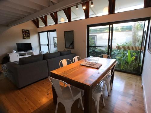 a living room with a wooden table and a couch at Treetops Everglades Villa in Byron Bay