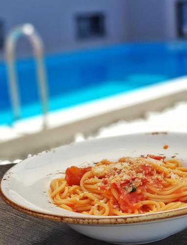 a plate of pasta with sauce and cheese on a table at Hotel Yakinthos in Paralia Katerinis
