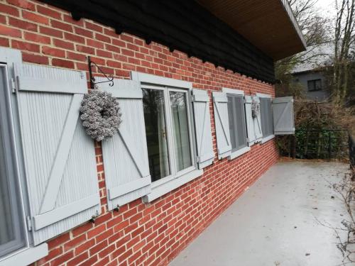 a brick building with white windows and a wreath at Au Bord De L'eau in Durbuy