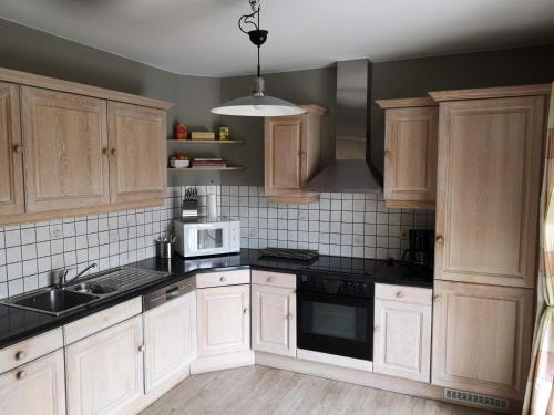 uma cozinha com armários de madeira e bancadas pretas em Au Bord De L'eau em Durbuy