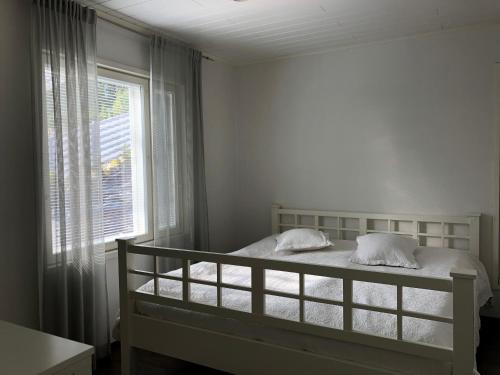 a white bedroom with a bed and a window at Villa Kalliorinne in Jyväskylä
