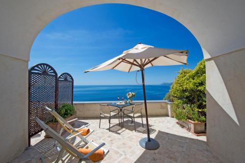 a patio with a table and chairs and an umbrella at Villa Il Frantoio and Lilmar in Praiano