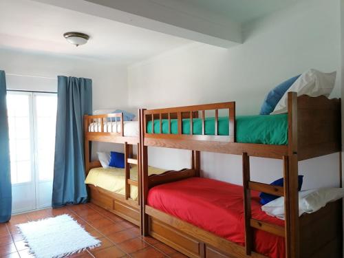 two bunk beds in a room with a window at Vivenda Framboesa in Vila Nova de Milfontes