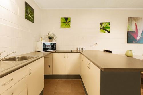 a kitchen with a sink, stove, microwave and cabinets at Cascade Gardens in Cairns