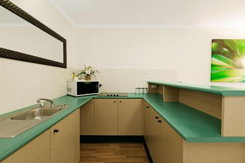 a kitchen with a sink and a microwave at Cascade Gardens in Cairns