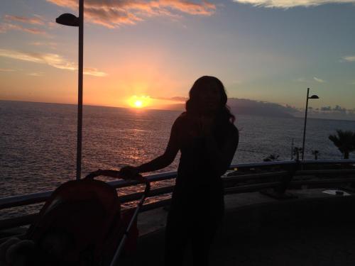 a woman standing in front of the ocean at sunset at WIFI TENERIFE SUR GUEST HOUSE in Granadilla de Abona