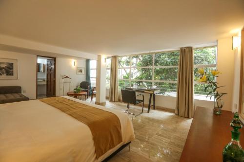 a bedroom with a bed and a desk and a large window at Casa Comtesse in Mexico City