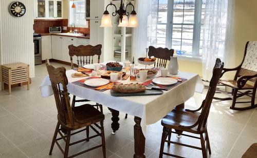 een eettafel met een wit tafelkleed en stoelen bij Gîte Au Blanc Marronnier in Racine