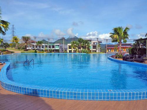 a large blue swimming pool with palm trees and buildings at Saichon Grand View in Ban Lam Rua Taek
