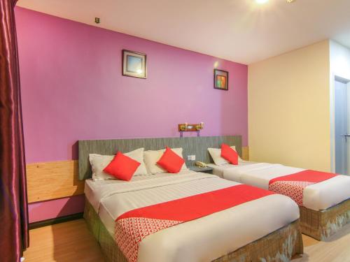 2 Betten in einem Zimmer mit lila Wänden in der Unterkunft Super OYO 43930 Hotel Esplanade in Sandakan