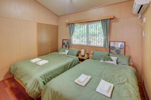 two beds in a small room with green sheets at Casa de R in Motobu