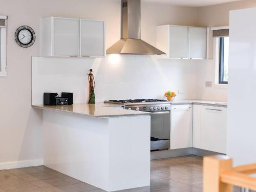 a kitchen with white cabinets and a stove at Anchor Belle Holiday Park in Cowes