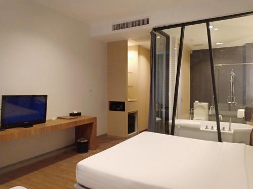 a bedroom with a bed and a tv and a bathroom at Vismaya Suvarnabhumi Hotel in Lat Krabang