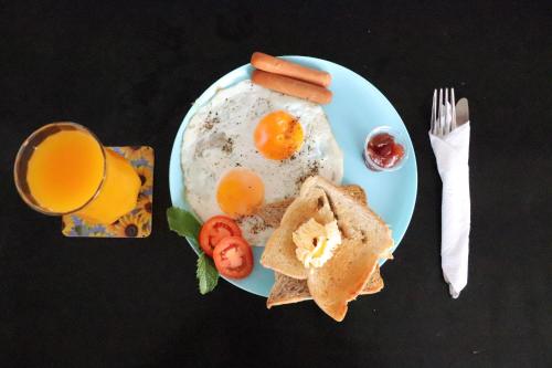 a plate of eggs and toast and a glass of orange juice at Miracle Colombo City Hostel in Colombo