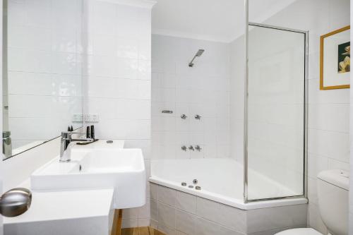 a white bathroom with a sink and a shower at Mantra PortSea in Port Douglas