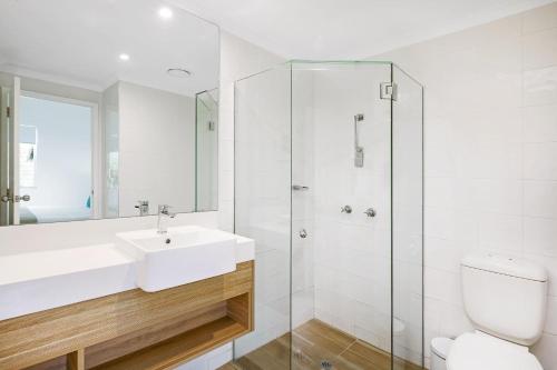 a white bathroom with a sink and a shower at Mantra PortSea in Port Douglas