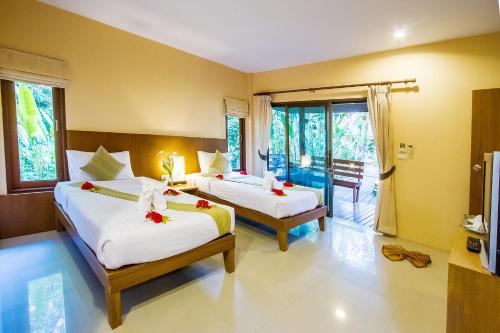 Sunda Resort في شاطيء آونانغ: غرفة نوم بسريرين وعليها ورد