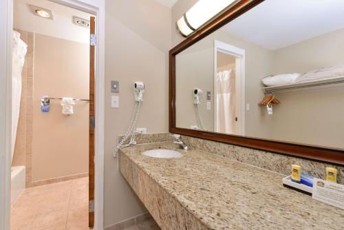 W łazience znajduje się umywalka i lustro. w obiekcie Best Western University Inn w mieście Fort Collins