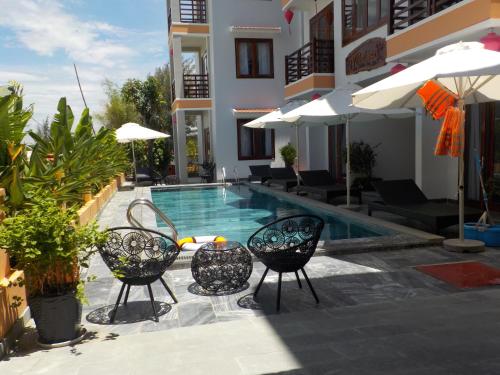 a swimming pool with two chairs and a hotel at Villa Loan A HOI AN in Hoi An