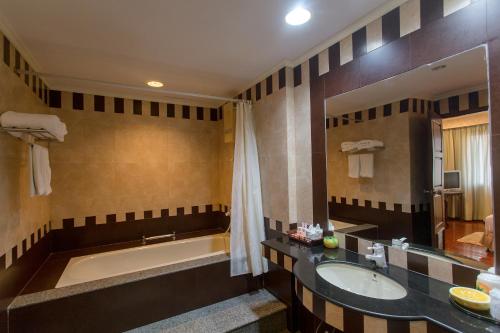 a bathroom with a tub and a sink at Tangerine Ville Hotel in Fang