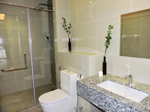 a bathroom with a toilet and a sink and a shower at Azure Residences by Sleepy Bear Paradigm Mall in Petaling Jaya