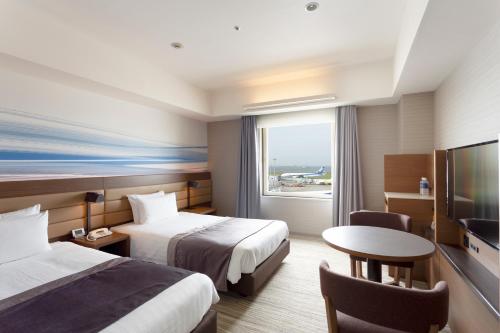 a hotel room with two beds and a table and a television at Haneda Excel Hotel Tokyu Haneda Airport Terminal 2 in Tokyo