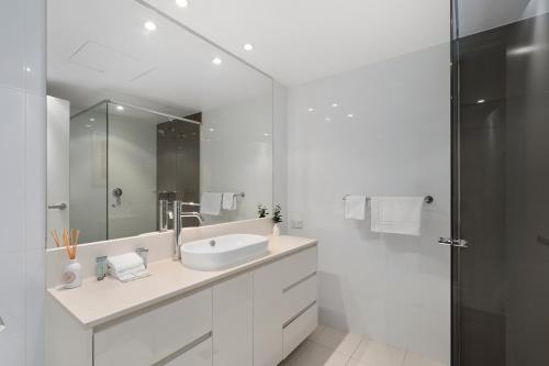 a white bathroom with a sink and a shower at H-Residences - GCLR in Gold Coast