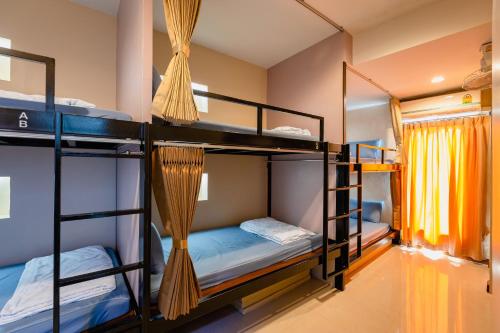 a room with three bunk beds and a window at Restiny Hostel in Bangkok