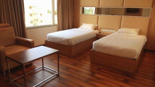 a hotel room with two beds and a table at Hotel Smart City Park Inn in Tada