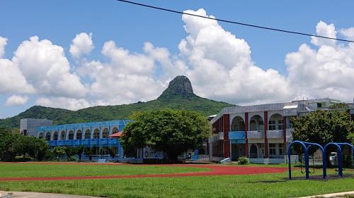 a building with a mountain in the background at Ching Ji Ming Inn in Kenting