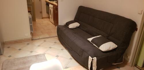 - un canapé noir avec deux oreillers dans le salon dans l'établissement Residence Caroline T2 clim parking, à La Grande Motte