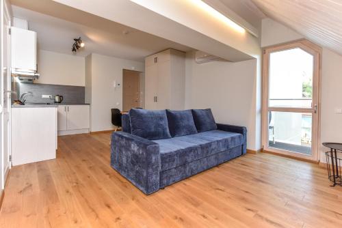 a living room with a couch and a kitchen at Gėlių terasos - studija su balkonu in Juodkrantė